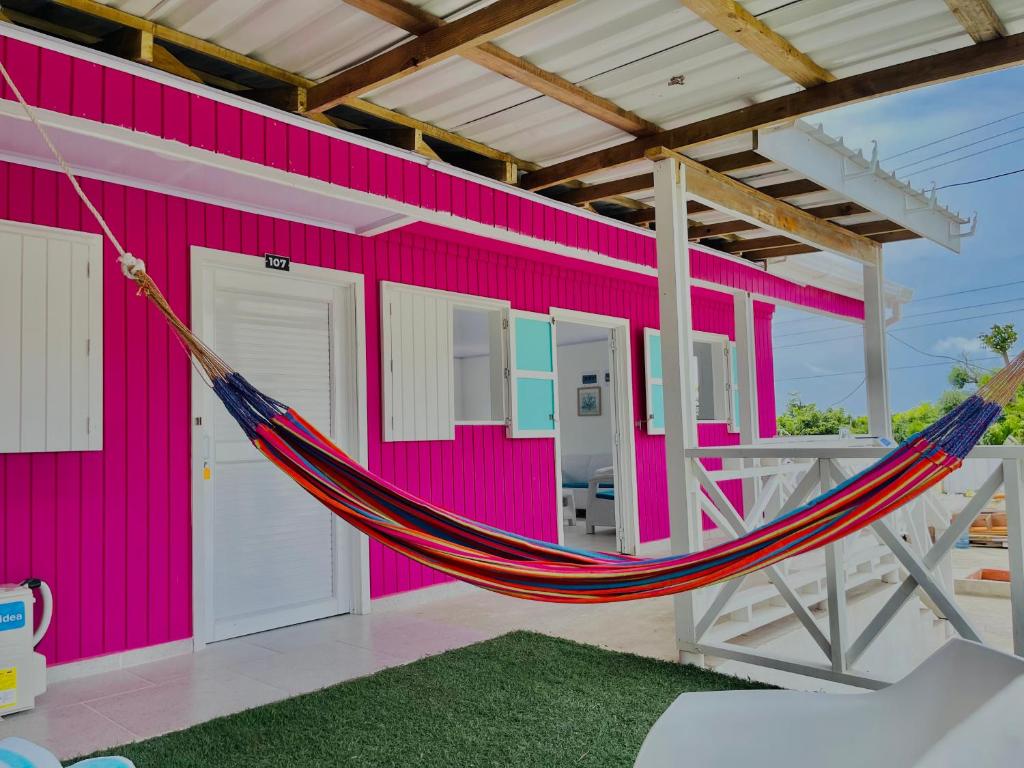 a hammock hanging outside of a pink building at Posada Camp Inn Providencia in Providencia