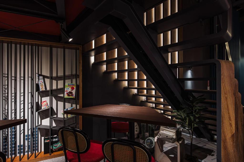 a room with a table and chairs and a spiral staircase at OLAH Poshtel - Taichung Station in Taichung