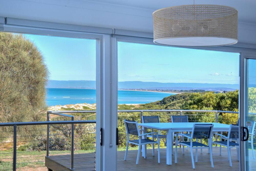 a table and chairs on a balcony with a view of the ocean at Sandbar Beach House in Coles Bay