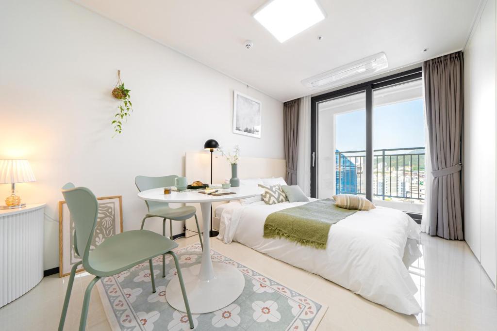 a white bedroom with a bed and a table and chairs at Urbanstay Busan Cityhall in Busan