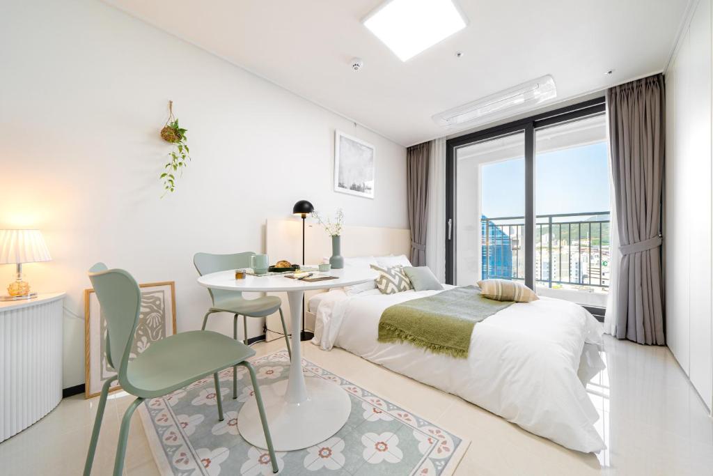 um quarto branco com uma cama, uma mesa e cadeiras em Urbanstay Busan Cityhall em Busan