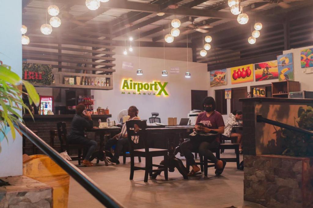 a group of people sitting at tables in a restaurant at Airport X Managua in Managua