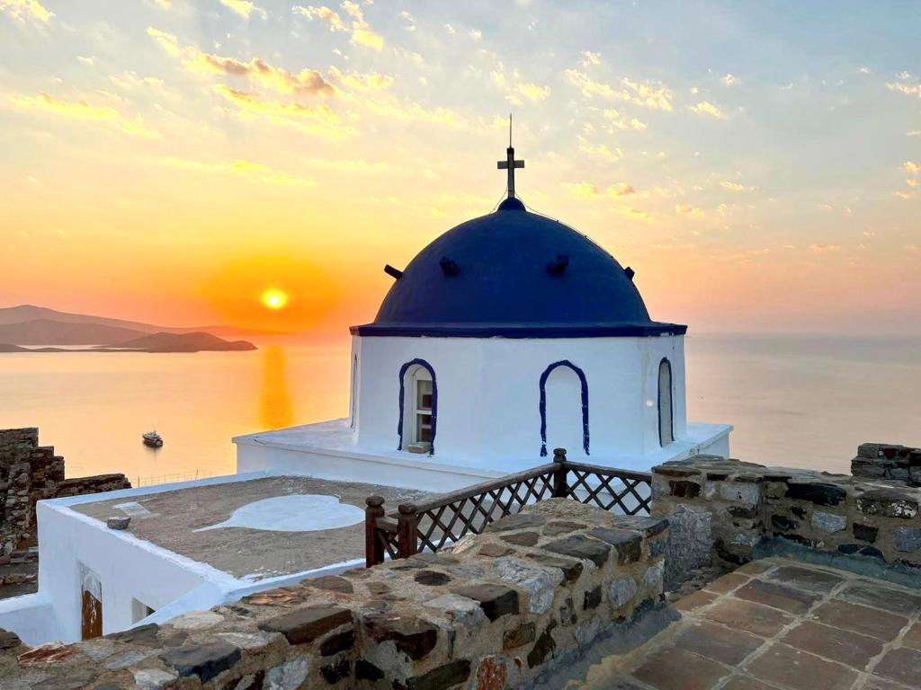 a church on the edge of the water with a sunset at Gerani Deluxe Houses 2 in Astypalaia