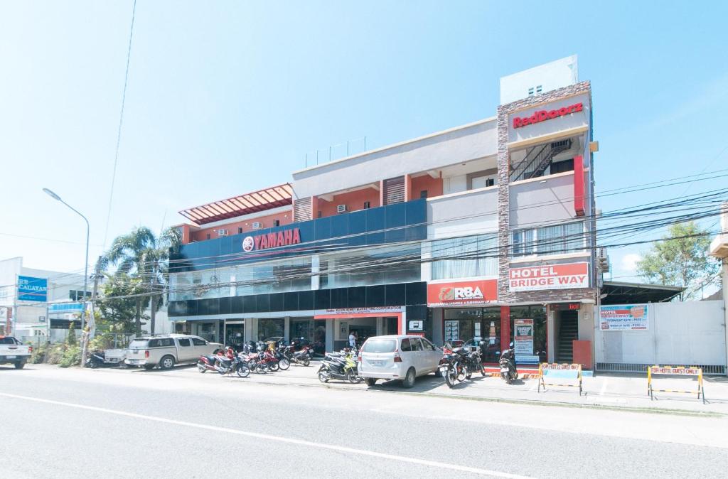 a building with motorcycles parked in front of a street at RedDoorz @ Bridgeway Hotel Tuguegarao City in Tuguegarao City