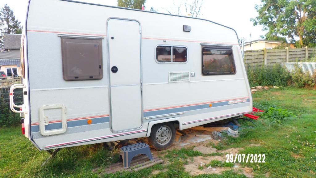 a white trailer is parked in a yard at Une pause... Quelque part in Le Torp-Mesnil