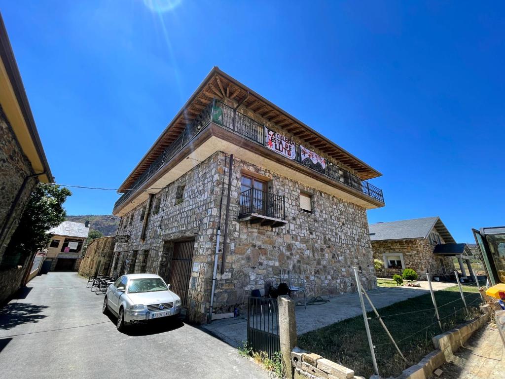 a stone building with a car parked in front of it at La Guarida de la Lleira in Ferreras de Arriba