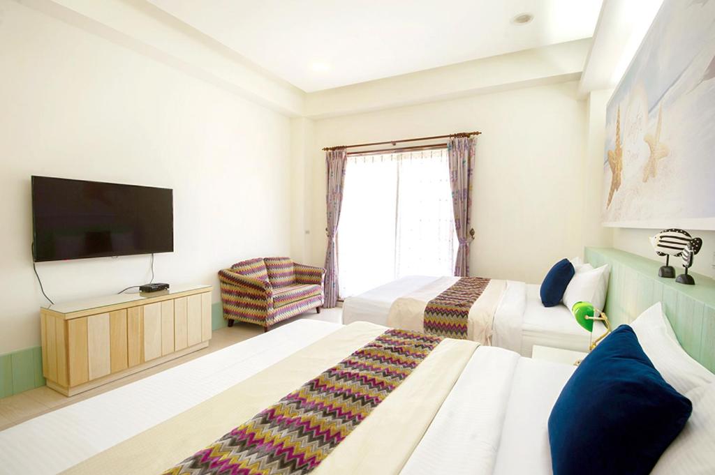 a hotel room with two beds and a flat screen tv at Spring Villa in Dongshan