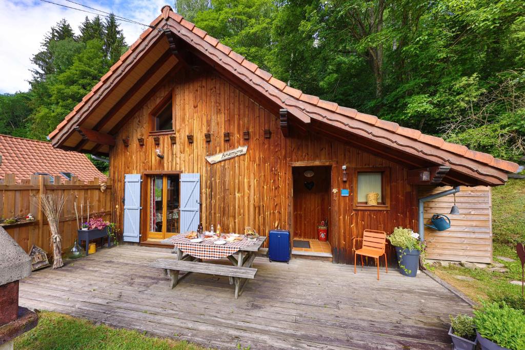 eine Holzhütte mit einem Tisch davor in der Unterkunft Chalet Anemone in Soultzeren