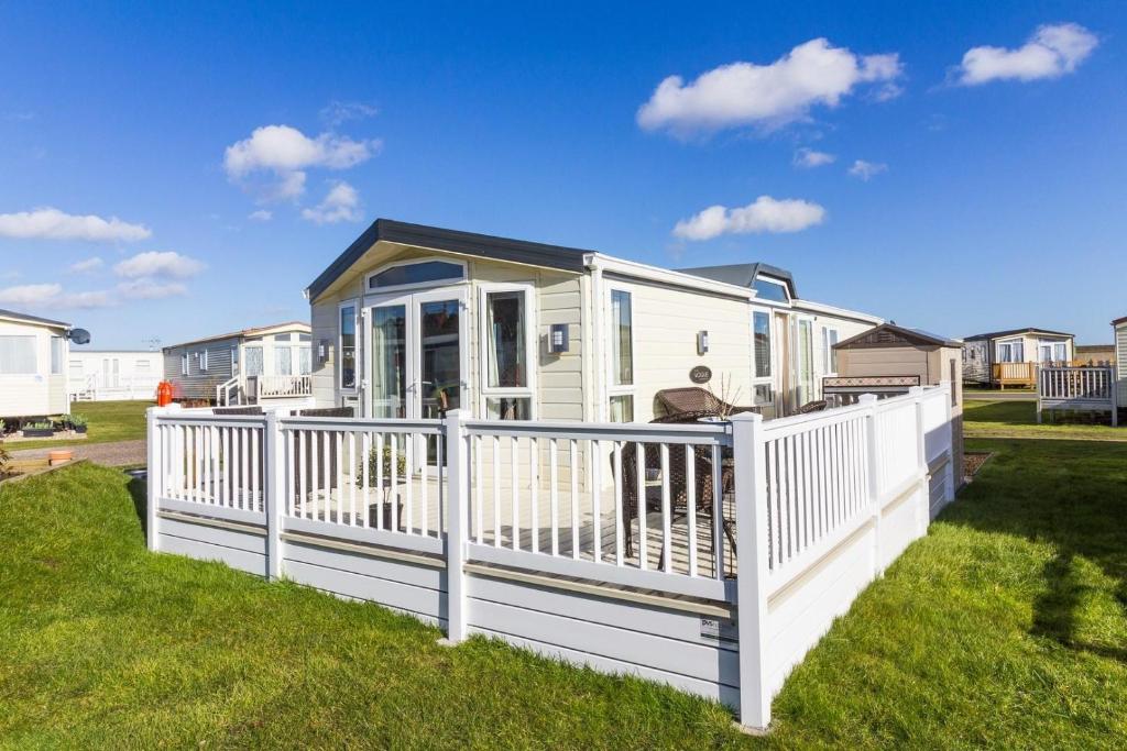 a mobile home with a white fence at Beautiful, Pet Friendly Caravan By The Beach In Suffolk Ref 40126nd in Lowestoft