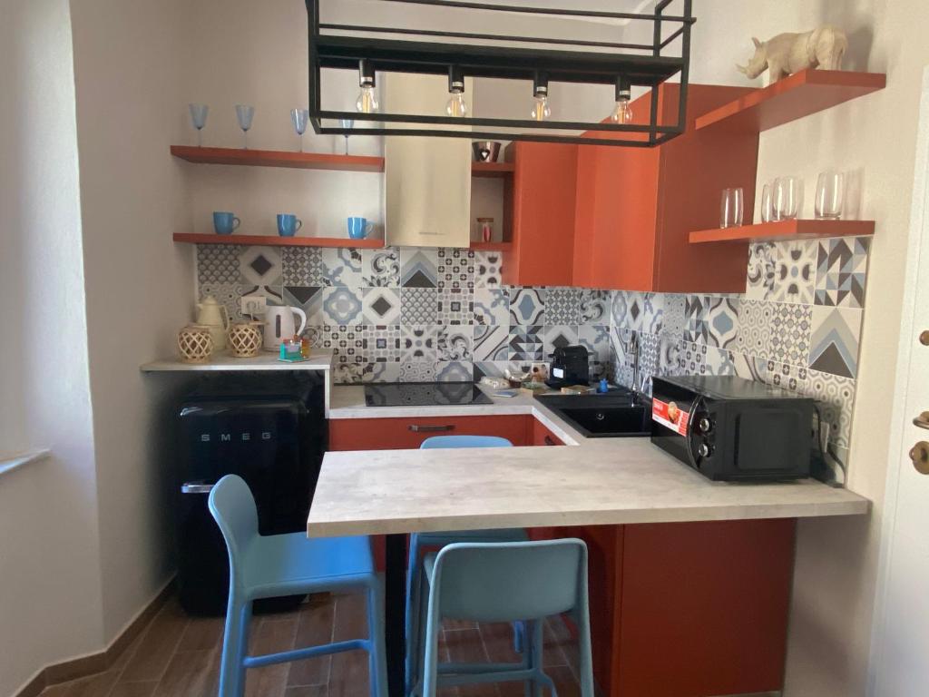 a kitchen with red cabinets and blue bar stools at LaCAsina Appartamento delizioso/nuovo Grosseto centro in Grosseto