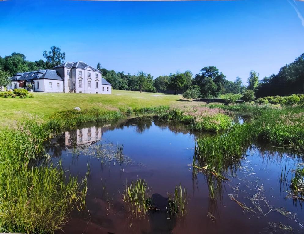 a house in a field next to a pond at Glassford House in Glasgow