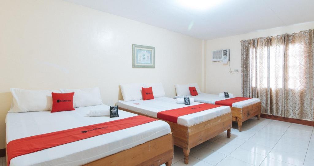 a room with two beds with red and white pillows at RedDoorz @ Goldland Spring Resort Urdaneta City in Urdaneta