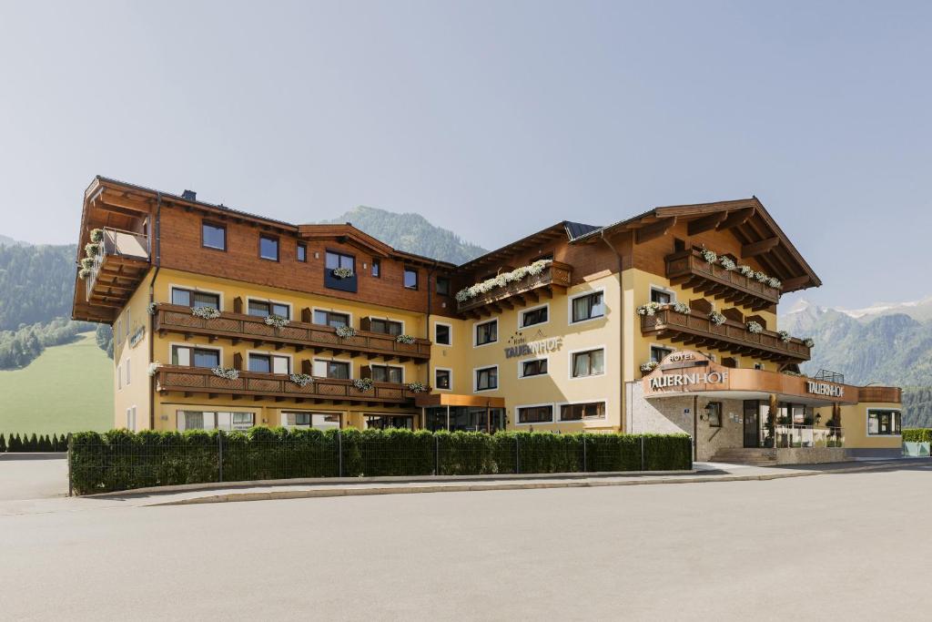 a large building with mountains in the background at Hotel Tauernhof in Kaprun