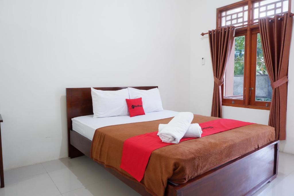 Reddoorz at Bale Eja Syariah Senggigi في Montongbuwoh: غرفة نوم عليها سرير وفوط