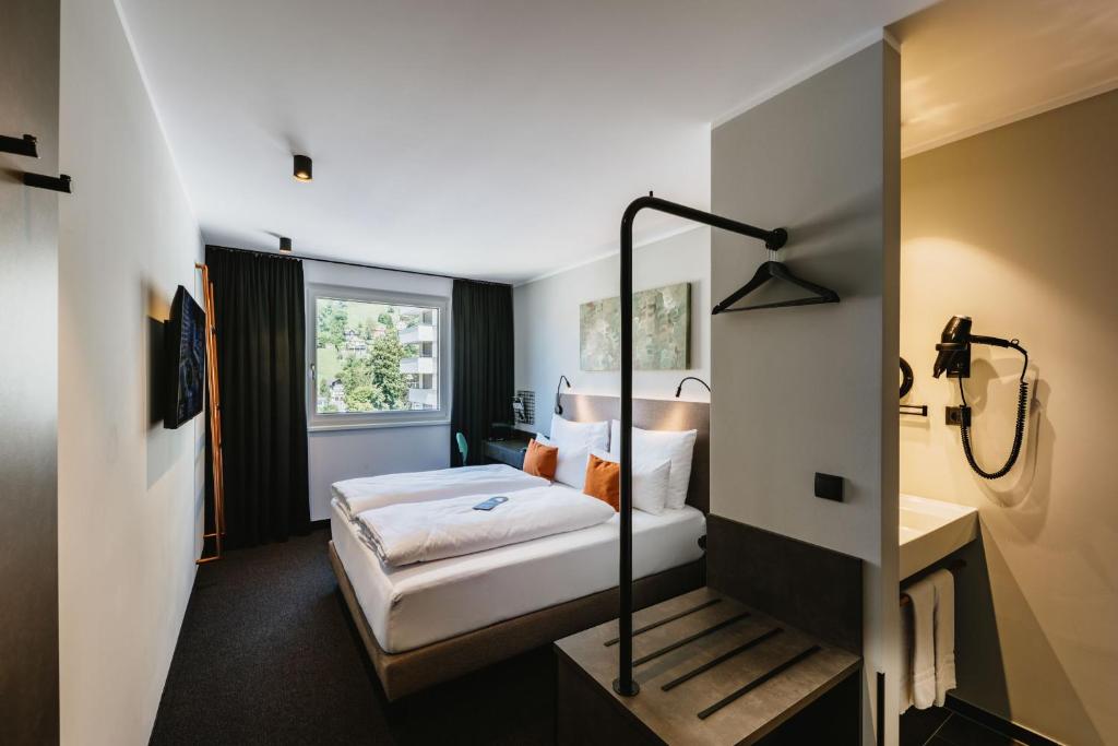 a hotel room with a bed and a bathroom at NIGHT INN Hotel Bahnhofcity Feldkirch in Feldkirch