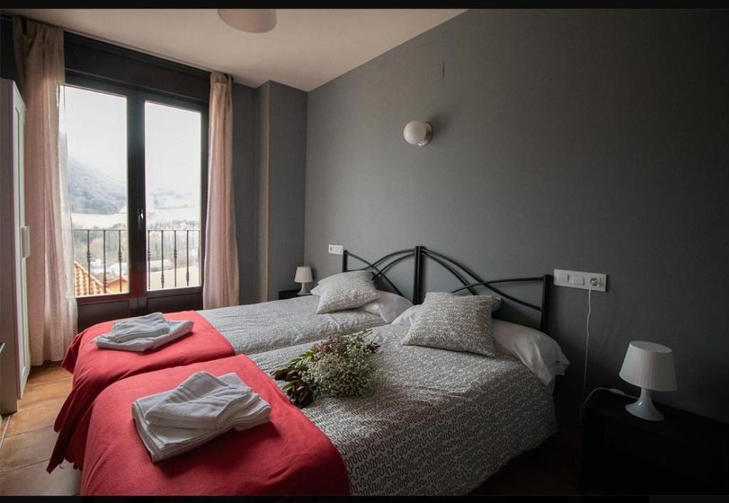 een slaapkamer met een bed met rode lakens en een raam bij La Morada de San Millán in San Millán de la Cogolla