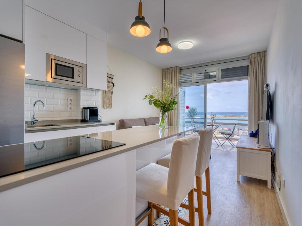 a kitchen with white cabinets and a counter with chairs at Marsin Canteras in Las Palmas de Gran Canaria