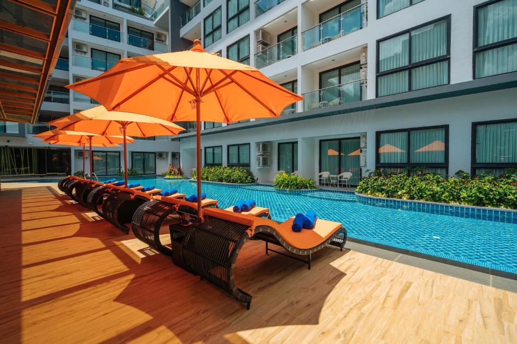 a row of chairs with umbrellas next to a swimming pool at Wekata Luxury in Kata Beach