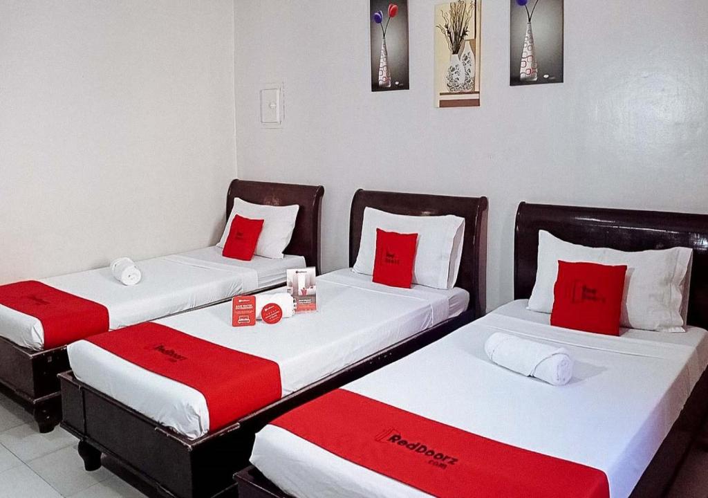 two beds in a room with red and white pillows at RedDoorz near Ormoc Port Terminal in Ormoc