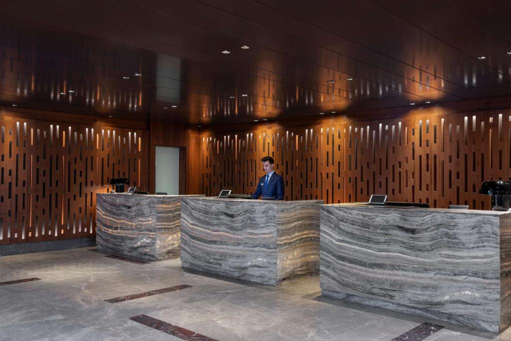 a man is standing behind a counter in a lobby at Radisson Blu Hotel & Spa, Istanbul Tuzla in Istanbul