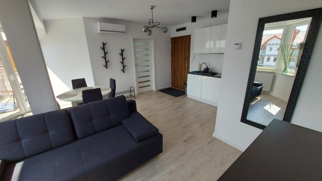 a living room with a blue couch and a kitchen at Apartamenty Baltic Korona B19 in Darłowo