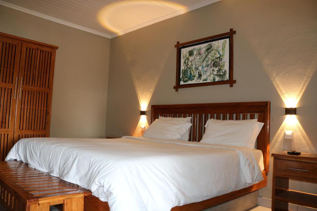 a bedroom with a large white bed with two lights at Pescador Villas in Inhambane