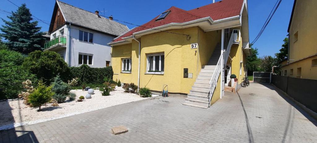 a yellow house with a staircase in front of it at Hi-Bp Garden city Batsanyi Apartment 3 Rooms, Apartment upstairs near the city train with FREE PARKING in Budapest