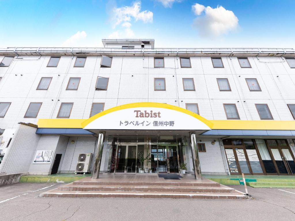 a tall white building with a sign on it at Tabist Travel Inn Shinshu Nakano in Nakano