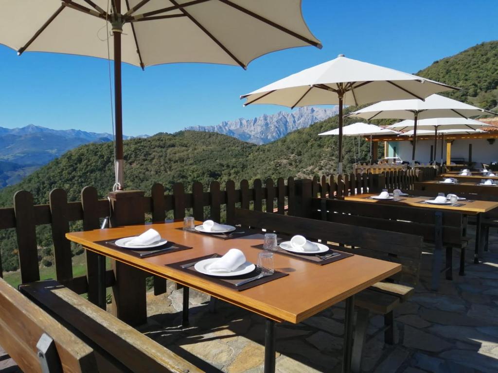 een restaurant met tafels met parasols en bergen op de achtergrond bij Casa Lamadrid in Cahecho