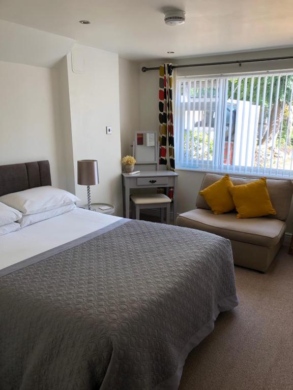 a bedroom with a bed and a couch and a window at The Copper Coin in Winford