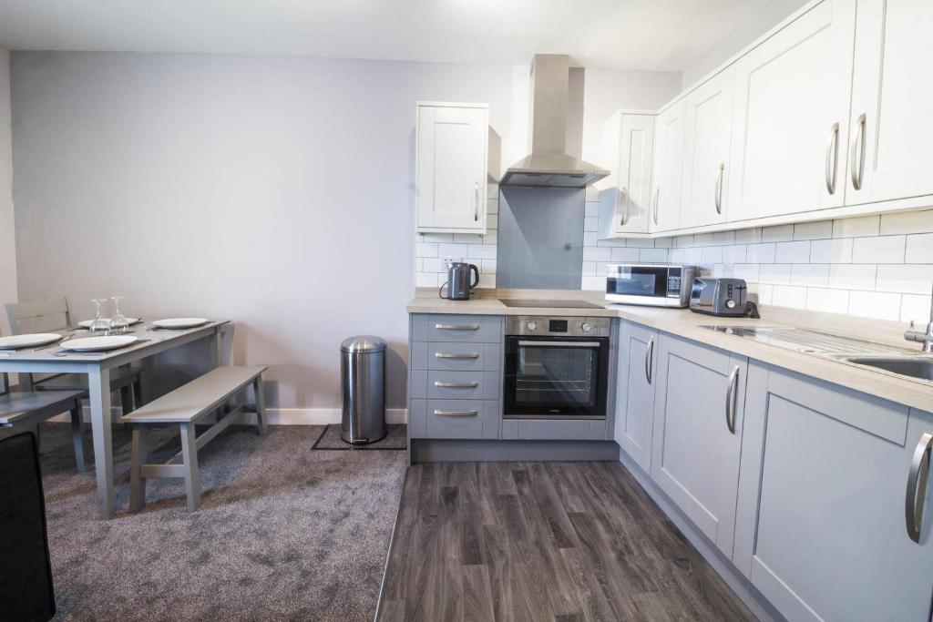 a kitchen with white cabinets and a table and a counter at Brilliant 4 Berth Seaside Apartment In Great Yarmouth, Norfolk Ref 99005s in Great Yarmouth