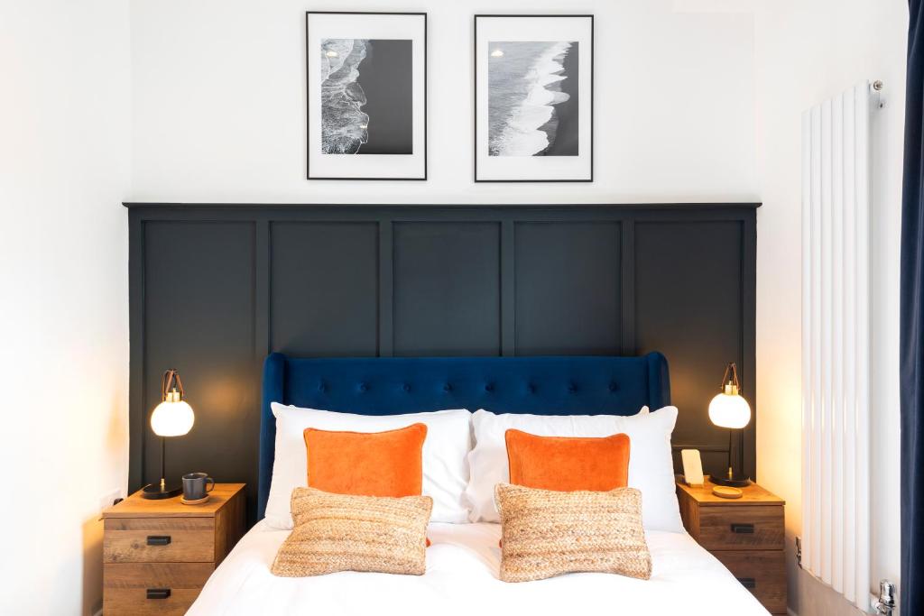 Crescent Apartments في نيوبورت: سرير مع اللوح الأمامي الأزرق وثلاث صور على الحائط