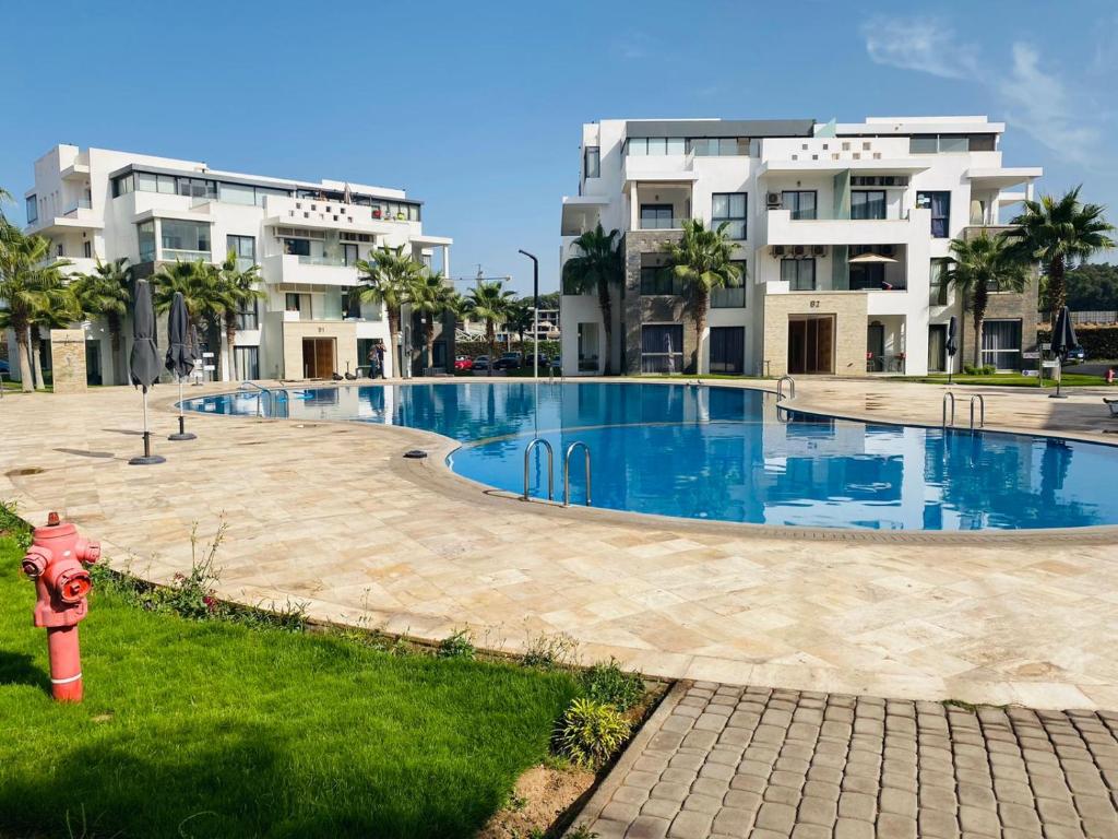 a red fire hydrant in front of a swimming pool at Hivernage, Superbe appartement dans une résidence in Agadir