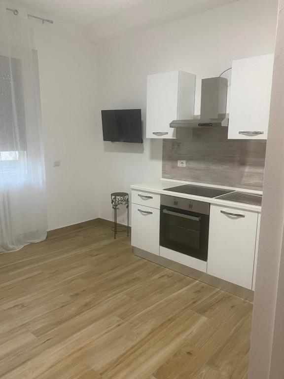 una cucina con elettrodomestici bianchi e pavimenti in legno di BeB via Sardegna a Legnano