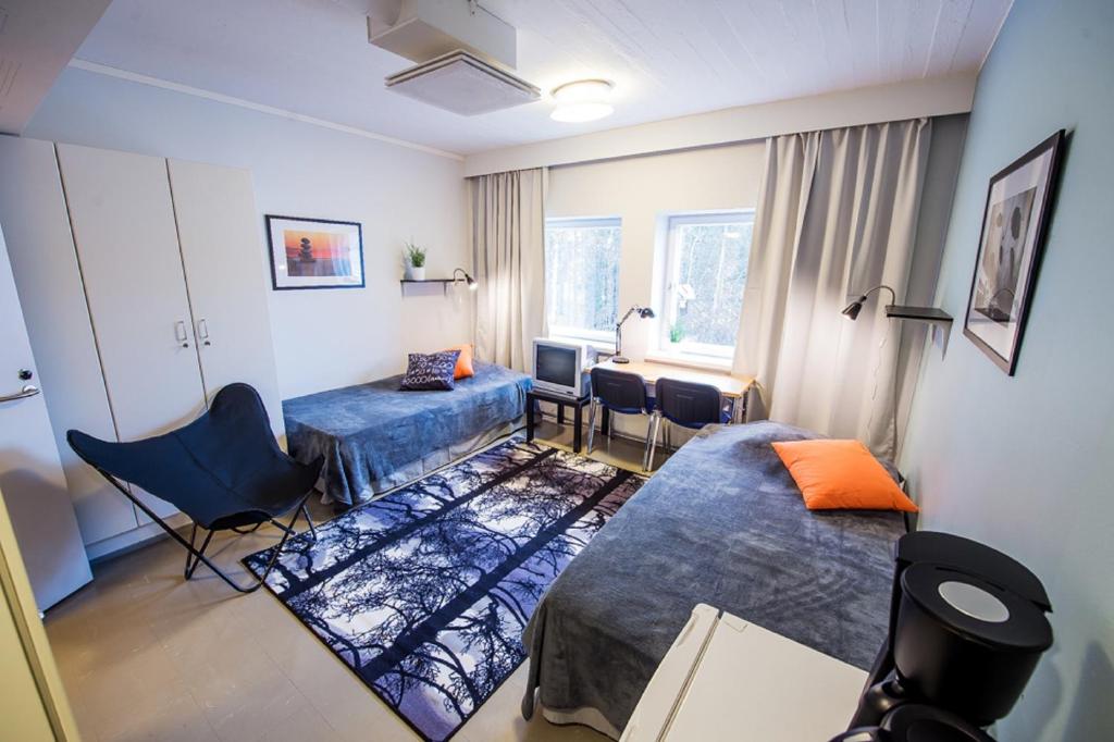 エスポーにあるフォレノム ホステル エスポー オタニエミのベッド2台、テーブル、デスクが備わる客室です。