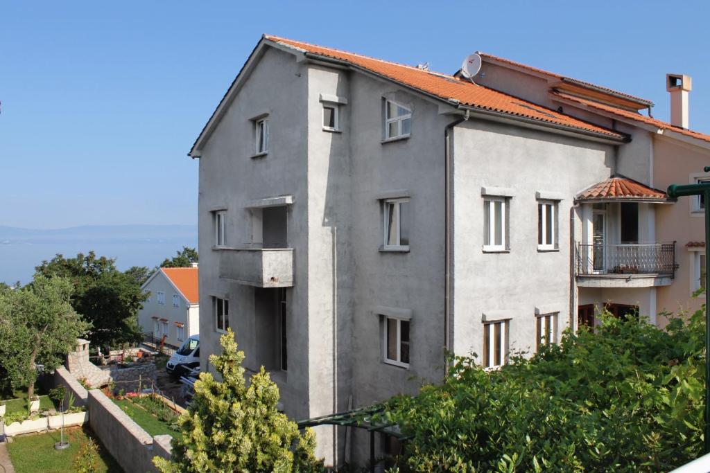 um edifício cinzento com um telhado vermelho em Apartment Njivice 5458a em Njivice