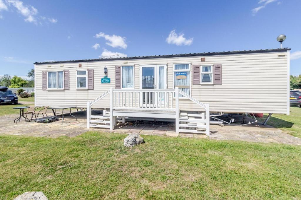 a mobile home with a porch and a yard at By The Seaside Dog Friendly Caravan At Haven Hopton In Norfolk Ref 80015w in Great Yarmouth