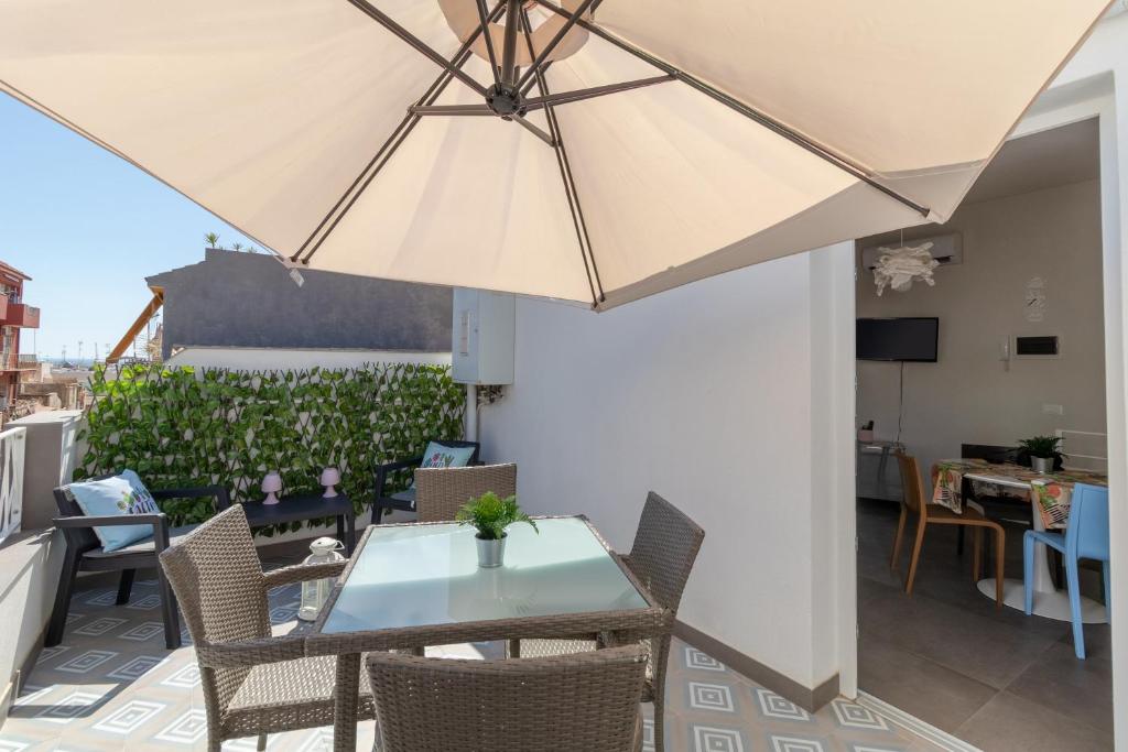 a table and chairs with an umbrella on a balcony at La Dimora della Luna in Pozzallo