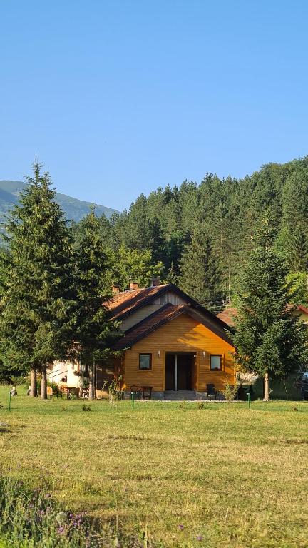 eine Blockhütte auf einem Feld mit Bäumen in der Unterkunft Apartmani Šarović in Tjentište