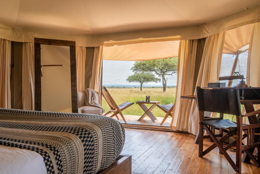 Schlafzimmer mit einem Bett und Blick auf ein Feld in der Unterkunft Cherero Camp in Serengeti-Savanne