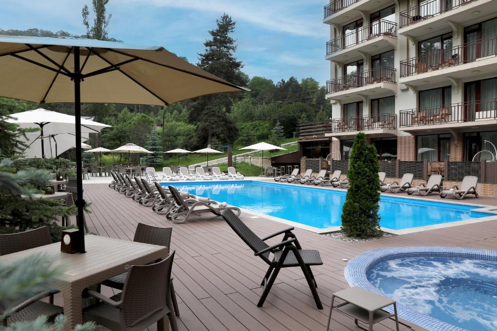 a hotel pool with chairs and a table and an umbrella at Best Western Plus Paradise Hotel Dilijan in Dilijan
