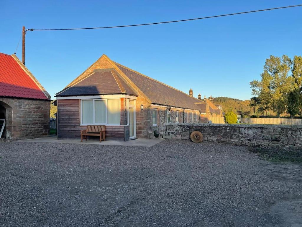 ein Backsteinhaus mit einer Bank davor in der Unterkunft Glen Cottage 8 Fenton Hill Farm in Wooler