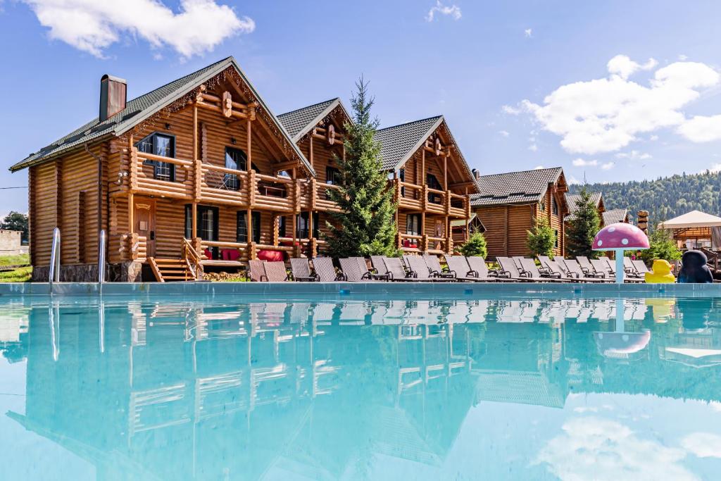 a log cabin with a swimming pool in front of a house at Красна Поляна Family Club Resorts in Bukovel