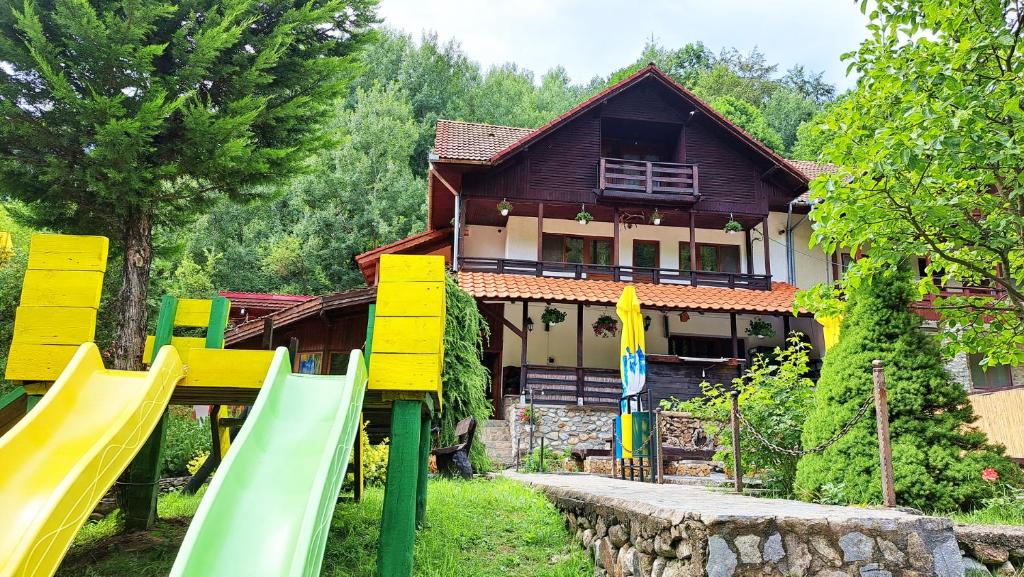 una casa con parque infantil frente a una casa en Hanul Vanatorului, en Gureni