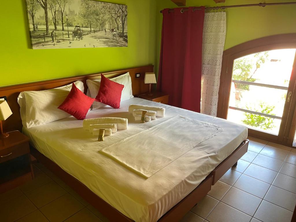 a bedroom with a large bed with red pillows at Hotel Al Bosco in Sona