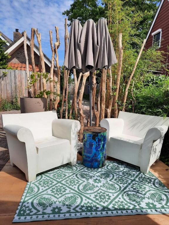 two white chairs and an umbrella on a rug at Arthouse Lola in Bergen
