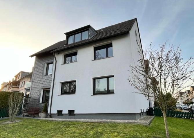 une maison blanche avec des fenêtres noires sur une cour dans l'établissement Ferienwohnungen Saarn, à Mülheim