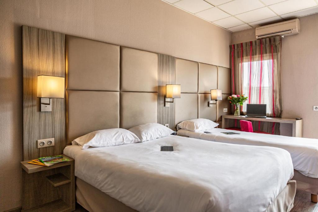 a hotel room with two beds and a window at Le Trèfle in Portet-sur-Garonne