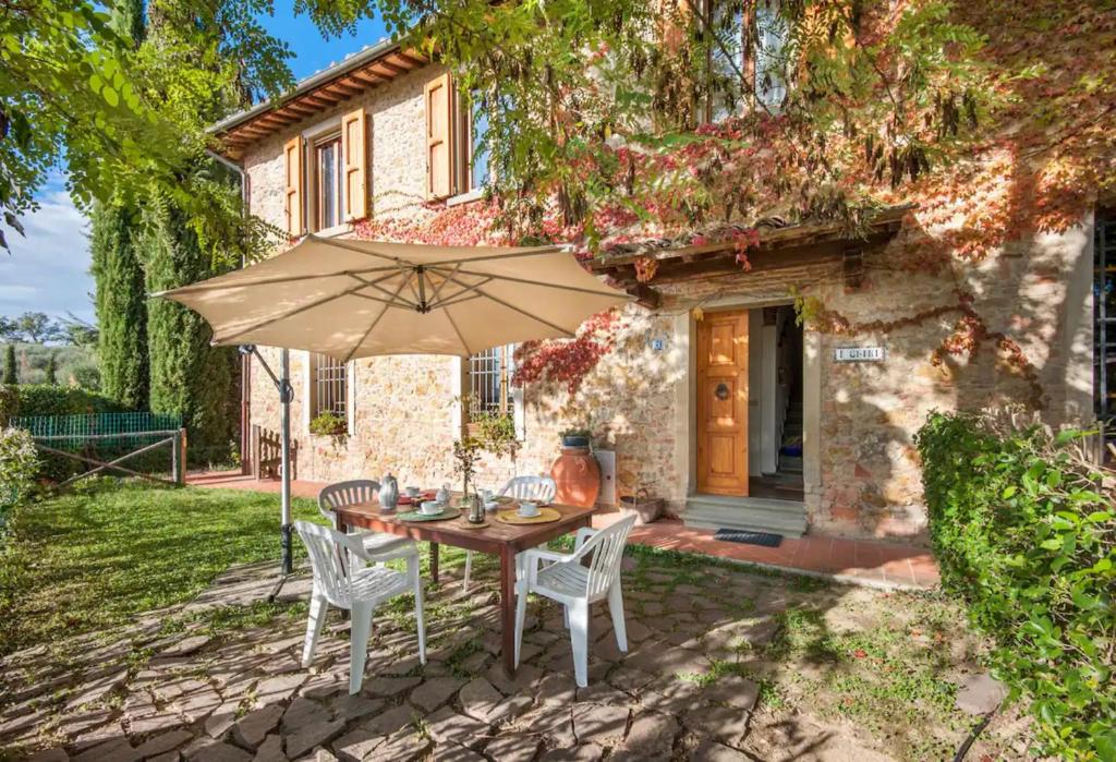 a table and chairs with an umbrella in front of a house at La Ripa - Appartamento I Ghiri in San Gimignano