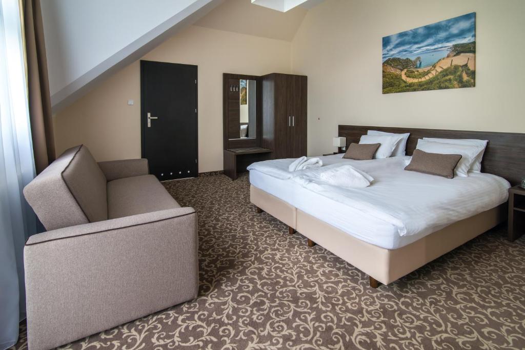 - une chambre avec un grand lit et une chaise dans l'établissement Hotel Biały Domek, à Wałcz